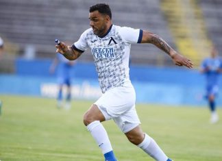 Емил Ангелов вярва в Левски: Такива мачове се печелят с характер Soccer player in a white and blue geometric jersey runs with the ball on a green pitch, with stadium stands in the background.