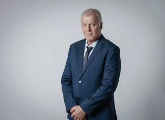 Наско Сираков за Palms Bet: Без тях Левски нямаше да се справи Portrait of an older man in a navy suit standing against a light gray background, looking at the camera.