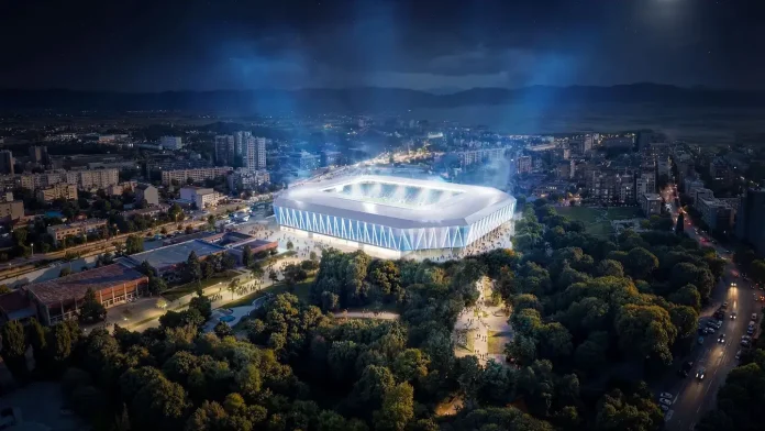Aerial nighttime view of a futuristic stadium glowing blue, nestled in a city park with surrounding streets and buildings.