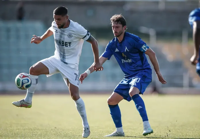 Soccer players sprint for the ball during a match; one in white with number 7, the other in blue close behind.