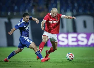 Георги Русев: Играхме равностойно с Левски, продължаваме напред Two soccer players duel for the ball on a green field, one in blue and one in red kit with a stadium background.