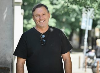 Гошо Гинчев сравни Папазки и Бостанджиев: И двамата са амбицирани да развиват ЦСКА и Левски Smiling man in a black t-shirt standing beside a concrete pillar on a sunny street, sunglasses hanging from his neckline.