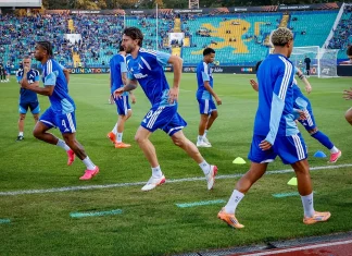 Кристиан Димитров за гола на Залцбург: Всичко стана за секунди Soccer players in blue training kits sprint across a green pitch during warm‑up before a match in a stadium.