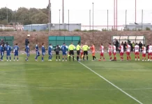 Левски II и Национал си поделиха точките след нулево равенство Two soccer teams in blue and red uniforms line up on the field for a pre-match handshake with referees nearby.