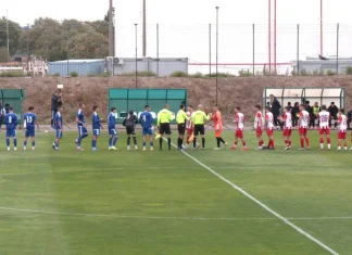 Левски II и Национал си поделиха точките след нулево равенство Two soccer teams in blue and red uniforms line up on the field for a pre-match handshake with referees nearby.
