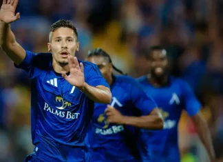 Рупанов разказа за тежката травма, баса с Ники Митов и работата с Веласкес Soccer player in a blue kit with Palms Bet logo raises hands in celebration on the field, teammates behind him.",