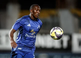 Алдаир – пълен профил и професионален път Male soccer player in a blue kit chasing a colorful ball on a field during a night match, focused and athletic posture.