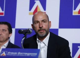 Атанас Бостанджиев се очаква на трибуните за мача на Левски с НЕК Man with a shaved head and gray beard speaks into a microphone at a press conference, with another man beside him and a blue logo backdrop.