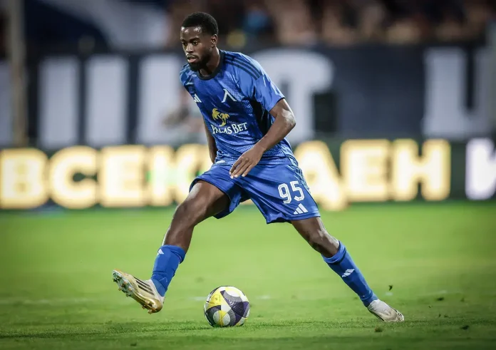 Soccer player in a blue uniform dribbling the ball on a green field during a match.