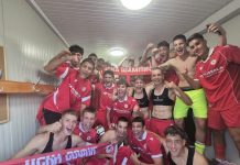 ЦСКА разби Левски при юношите и оглави класирането Group of young male soccer players in red uniforms celebrate in a locker room, many flexing arms and smiling.