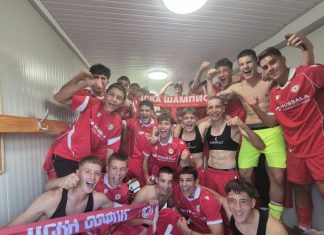 ЦСКА разби Левски при юношите и оглави класирането Group of young male soccer players in red uniforms celebrate in a locker room, many flexing arms and smiling.
