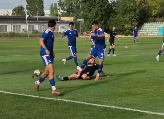 Дубълът на Левски надви Пирин в Разлог Soccer players in blue uniforms contest the ball on a grass field as a tackler in black attempts to stop them on the ground nearby