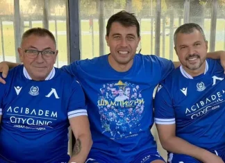 Голово шоу между легенди на Левски и лекари в благотворителен мач Three men in blue soccer jerseys sit on a bench with arms around each other, smiling at the camera.