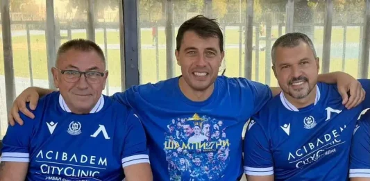 Голово шоу между легенди на Левски и лекари в благотворителен мач Three men in blue soccer jerseys sit on a bench with arms around each other, smiling at the camera.