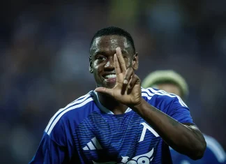 Хуан Переа: история и постижения на футболиста Soccer player in a blue jersey celebrating on the field, holding up three fingers toward the camera.