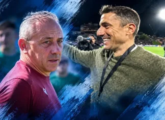 Илиан Илиев срещу Хулио Веласкес Two men on a football field share a moment, one in maroon shirt looking serious while the other smiles with a medal on a lanyard beside him, under stadium lights.