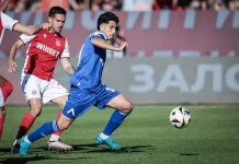 Кой ще замени Асен Митков срещу Черно море? Blue-shirted player runs toward the ball while a red-clad defender pursues on a grass soccer field.