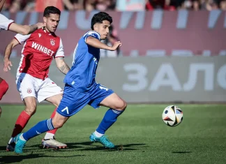 Кой ще замени Асен Митков срещу Черно море? Blue-shirted player runs toward the ball while a red-clad defender pursues on a grass soccer field.