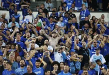 Левскарите изкупиха всички билети за гостуването на Черно море Huge crowd of blue-clad sports fans cheering in a stadium; a shirtless man with arms raised at center.