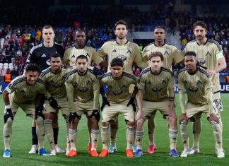 Левски с най-много победи в Европа – само осем тима са пред „сините“ Soccer team in beige away kits posing for a group photo on the field before a match, with stands in the background.