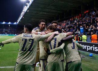 Левски направи това, което никой български отбор не успя Soccer players in beige uniforms huddle together in celebration on the pitch as spectators cheer in the stands in the background.