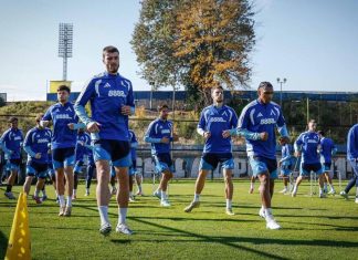 Левски обяви програмата си преди гостуването на Арда в Кърджали Soccer players in blue uniforms run through a training drill on a sunny green field, with cones and hurdles in front and stadium lights in the background.