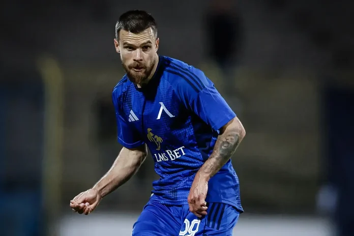 Soccer player in a blue kit sprinting on a dim field, LMS BET sponsor logo visible.