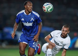 Левски поздрави Алдаир за рождения му ден Two soccer players on a field chase a ball in midair; blue jersey leads while a white jersey pursues.