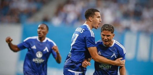Левски преследва първи точки и исторически пробив срещу НЕК Three soccer players in blue uniforms celebrate on the field, embracing and cheering.