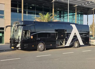 Левски пристигна в Германия, продължава към Нидерландия за мача с НЕК Black luxury tour bus with a large white A design on its side, parked in front of a glass-fronted building.