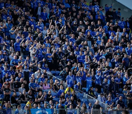 Левски пусна билетите за „Тича“ Large crowd of sports fans in blue, seated in a stadium, many clapping and cheering.