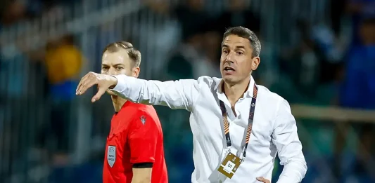 Левски се превърна в най-силния период в кариерата на Хулио Веласкес Soccer coach in a white shirt on the sideline, gesturing with his arm while a referee in red stands nearby during a match.