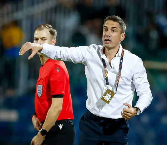 Левски се превърна в най-силния период в кариерата на Хулио Веласкес Soccer coach in a white shirt on the sideline, gesturing with his arm while a referee in red stands nearby during a match.