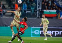 Левски ще преговаря с халф за нов договор Two players jump to head the ball during a soccer match, one in beige and the other in red and black.