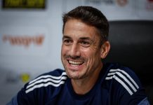 Левски търси голмайстор от висока класа Smiling man with short dark hair and stubble wearing a navy athletic shirt with white stripes, seated in a press/interview setting.