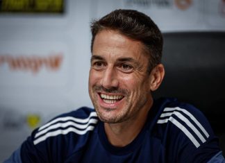 Левски търси голмайстор от висока класа Smiling man with short dark hair and stubble wearing a navy athletic shirt with white stripes, seated in a press/interview setting.