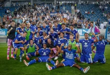 Левски търси първи точки в Лига Европа срещу разколебания НЕК Blue soccer team celebrates on the field with fans cheering in the stands behind them, posing for a victory photo.