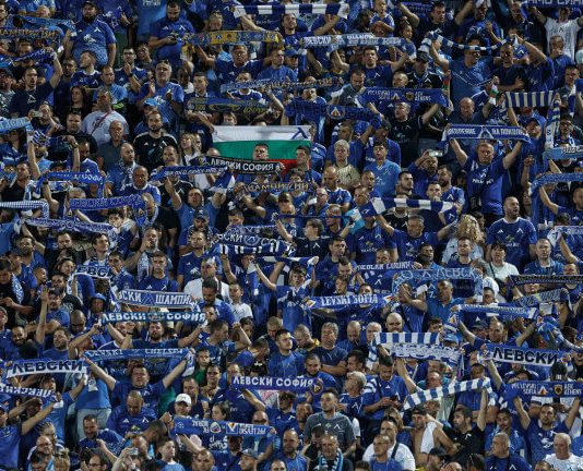 Левски с важна информация за феновете си за мача с Арда Crowd of blue-clad soccer fans in a stadium, many holding striped scarves overhead.