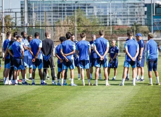 Левски влиза в подготовка за Черно море Soccer players in blue training kits stand in a circle on a green grass field during practice with a goal in the background.