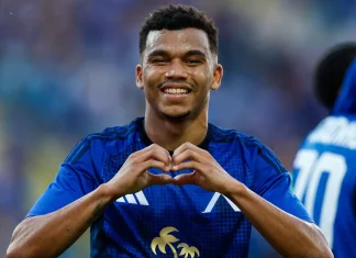 Майкон: кариера, отбори и факти Soccer player in a blue jersey smiling while forming a heart shape with his hands on the field.