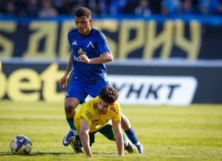 Майкон сбъдна детска мечта с Левски Soccer clash: a blue-team player challenges a yellow-team defender for the ball on a sunlit field, both near the ball.