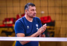Николай Желязков след четвъртата поредна Суперкупа на Левски: Показахме характер в най-важния момент Coach or team staff member in a blue T-shirt clapping in an indoor sports venue, with red seats in the background.