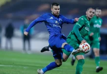 Обнадеждаващи новини за Радослав Кирилов Soccer player in a blue kit kicking a ball during a match, with a green-clad opponent nearby on the field.