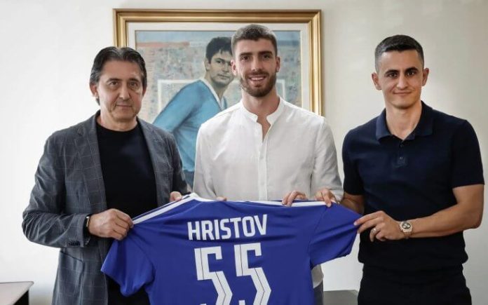 Three men posing indoors, holding a blue jersey with the name Hristov and number 55.
