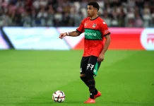 Проблеми в НЕК преди мача с Левски: Треньорът наказа млад нападател Soccer player in a red and green kit with number 77 dribbling a ball on a green pitch during a match.