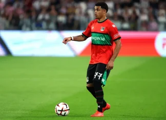 Проблеми в НЕК преди мача с Левски: Треньорът наказа млад нападател Soccer player in a red and green kit with number 77 dribbling a ball on a green pitch during a match.