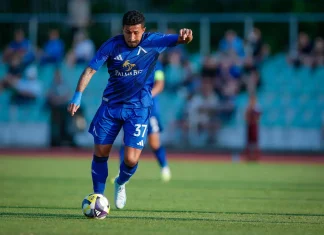 Рилдо Фильо – профил, статистика и кариера Soccer player in blue uniform dribbling a ball on a green field during a match, with spectators in the bleachers in the background