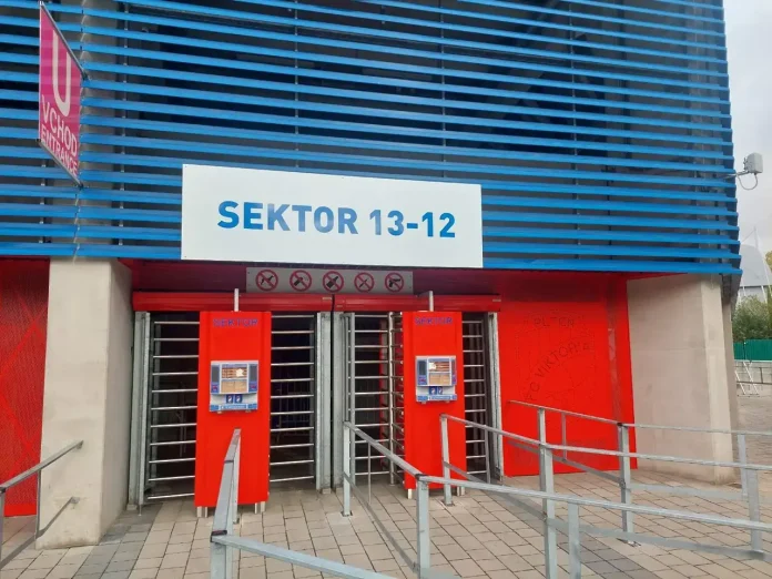 Entrance to Sector 13-12 with red turnstiles under a blue striped building façade.