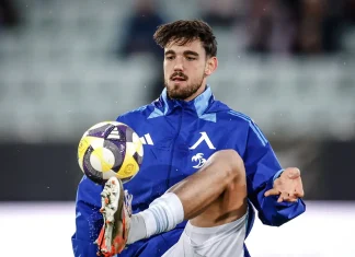 Стипе Вуликич: профил, отбори и резултати Soccer player in a blue training jacket traps a yellow-purple ball with his foot mid-action on the field.