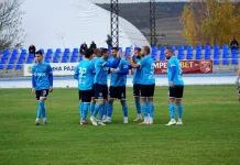 Струмска слава измъкна точка срещу дубъла на Левски Soccer players in blue kits form a huddle on a green field before a match with empty blue seats behind them.